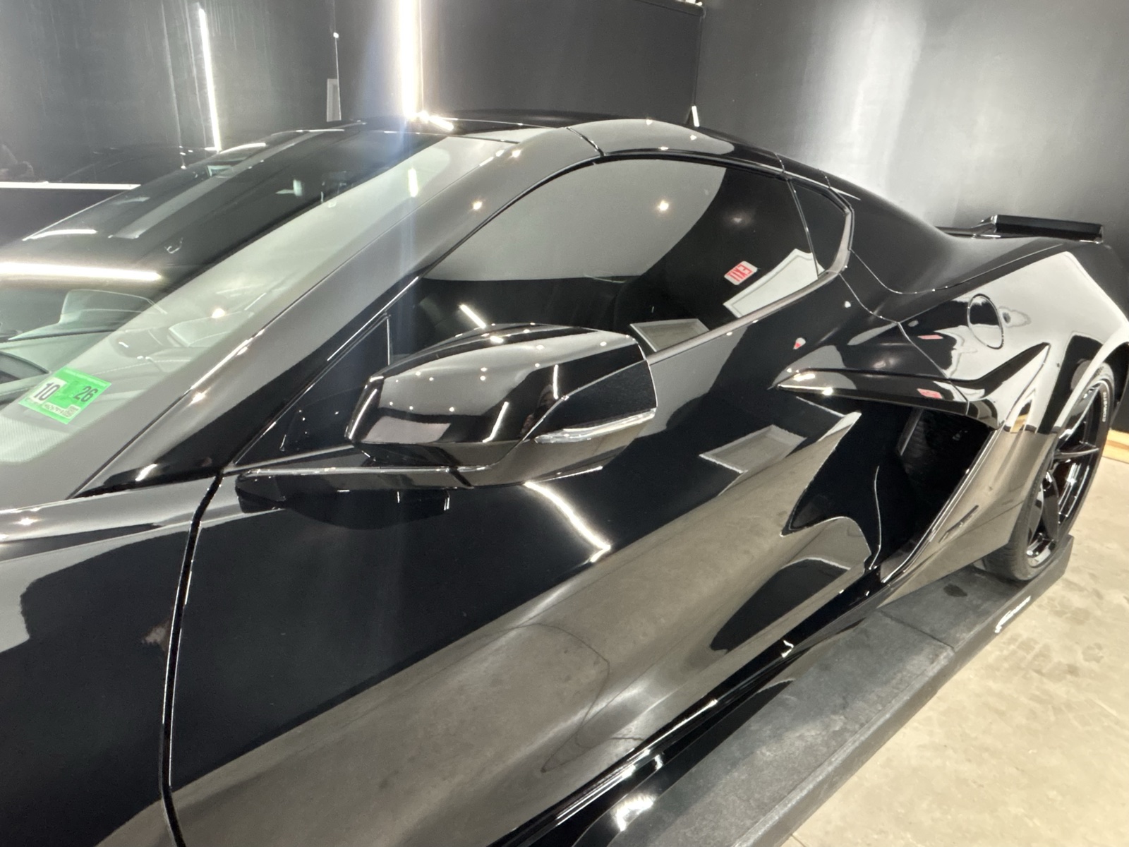 Black Corvette with dark window tint under the lights in the Coastal Details shop